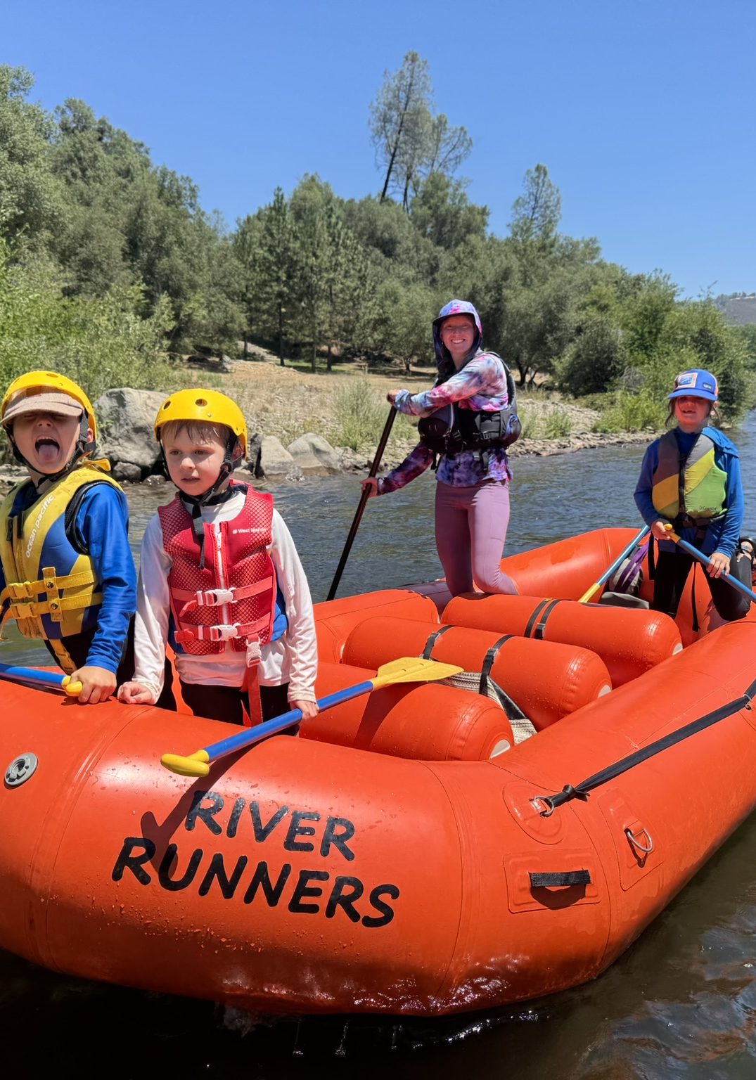 River Kids smiling in an orange raft on the South Fork of the American River